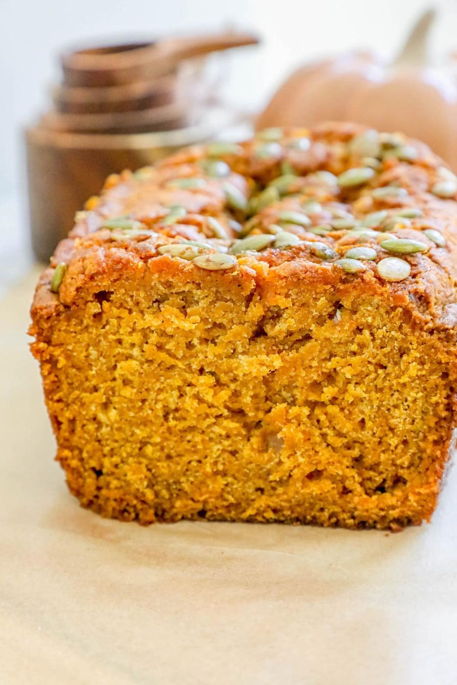 A slice of pumpkin bread with pumpkin seeds on a baking sheet.