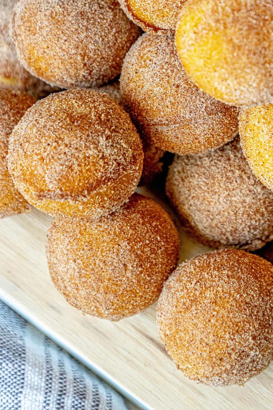 Peach donuts on a wooden cutting board served with easy baked cinnamon sugar donut holes.