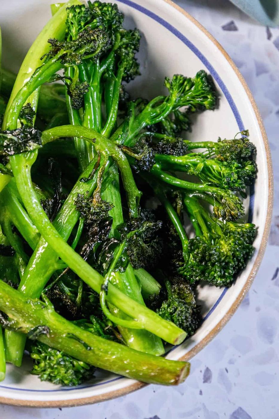 A bowl of sautéed broccolini on a table.
