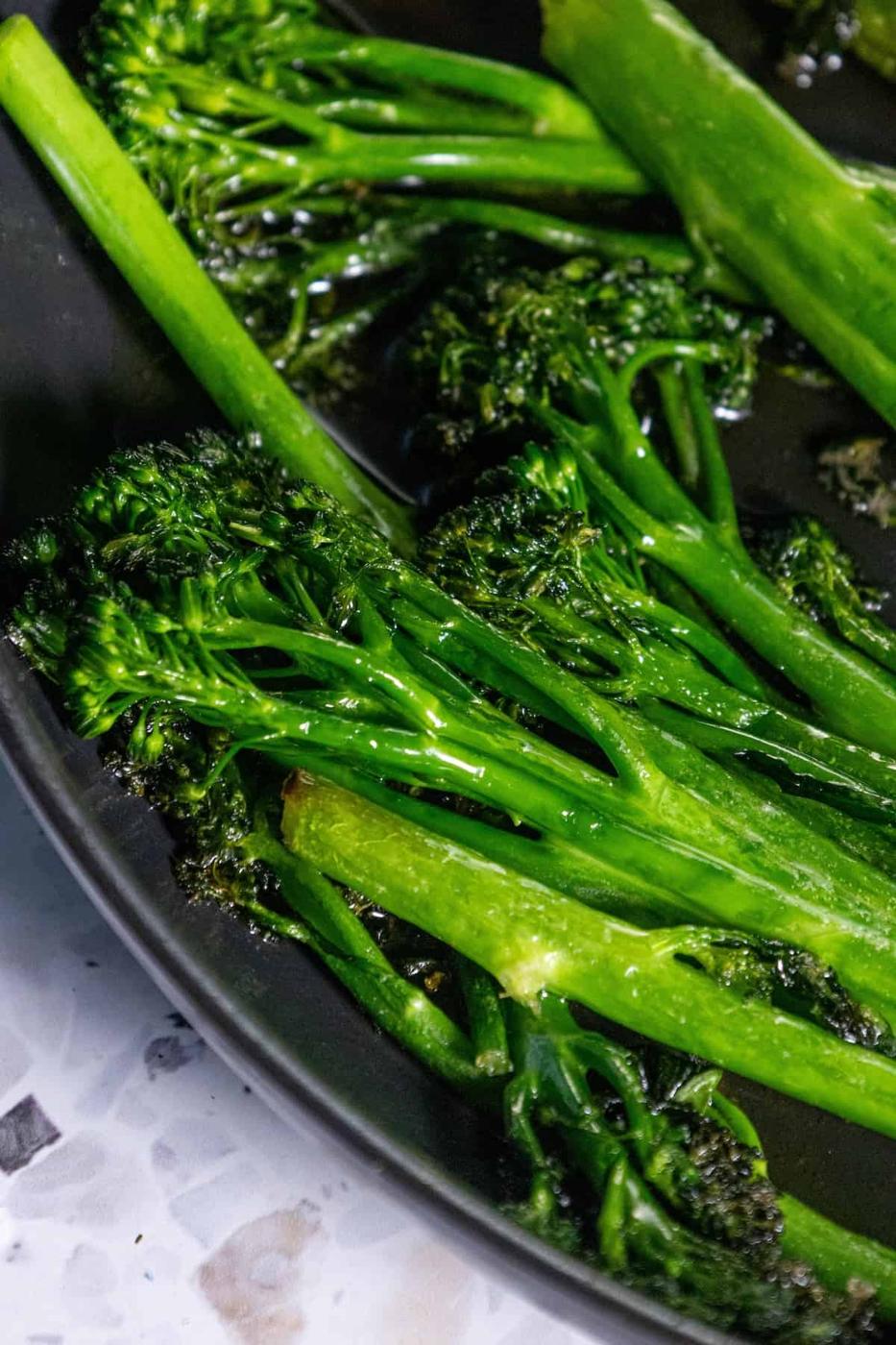 A plate of sautéed broccolini on a table.