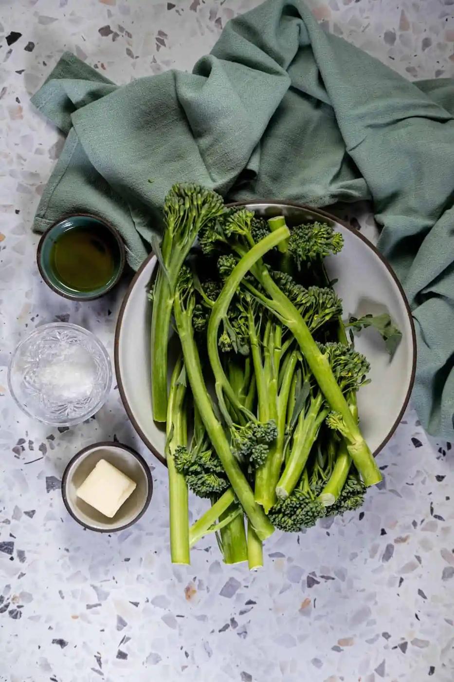 A bowl of broccoli and butter on a table, prepared with the keto baby broccoli recipe.