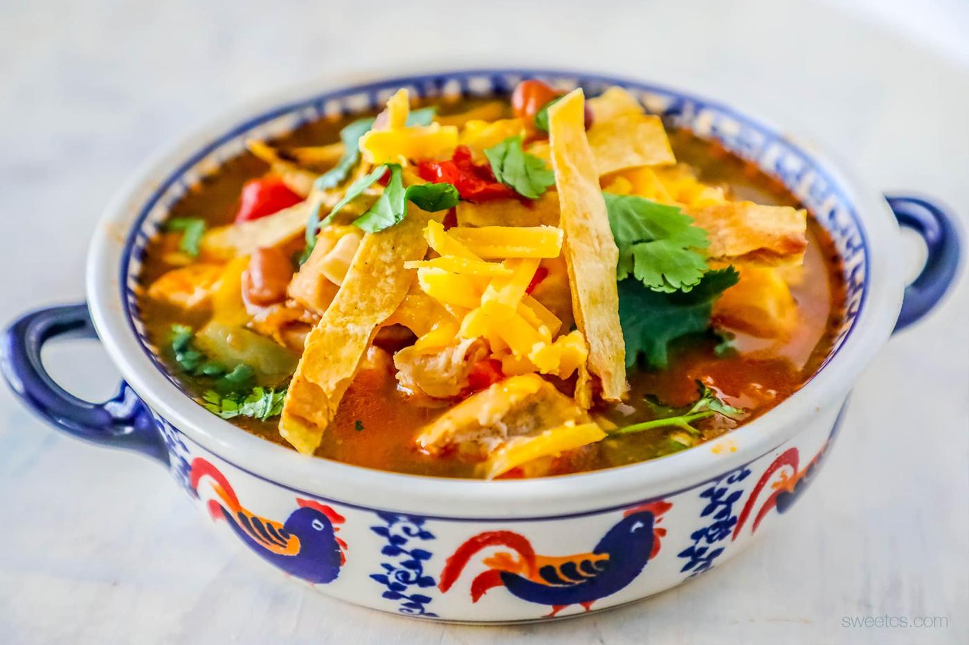soup with cilantro, cheese, and tortilla strips on it