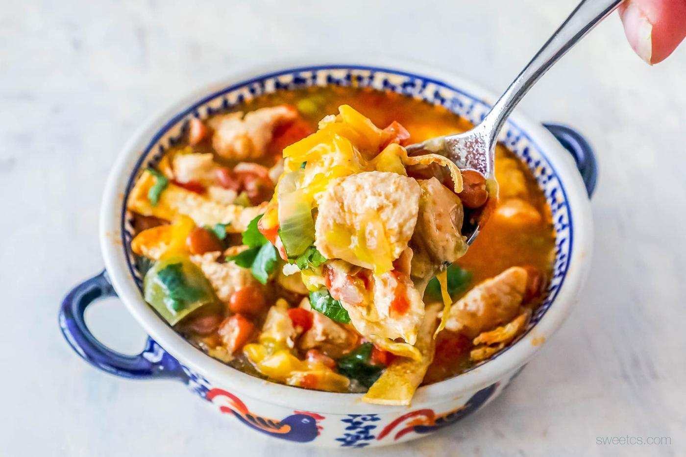 soup with cilantro, cheese, and tortilla strips on it