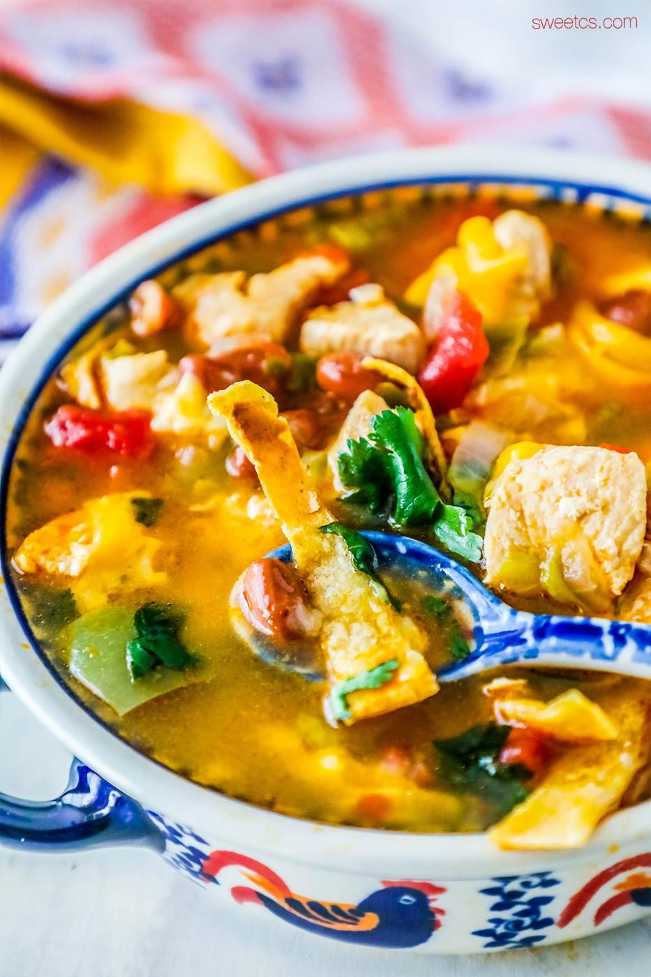 soup with cilantro, cheese, and tortilla strips on it