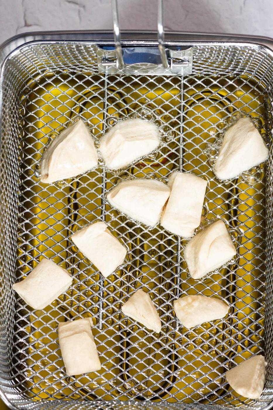 A wire mesh basket filled with pieces of fried bread.