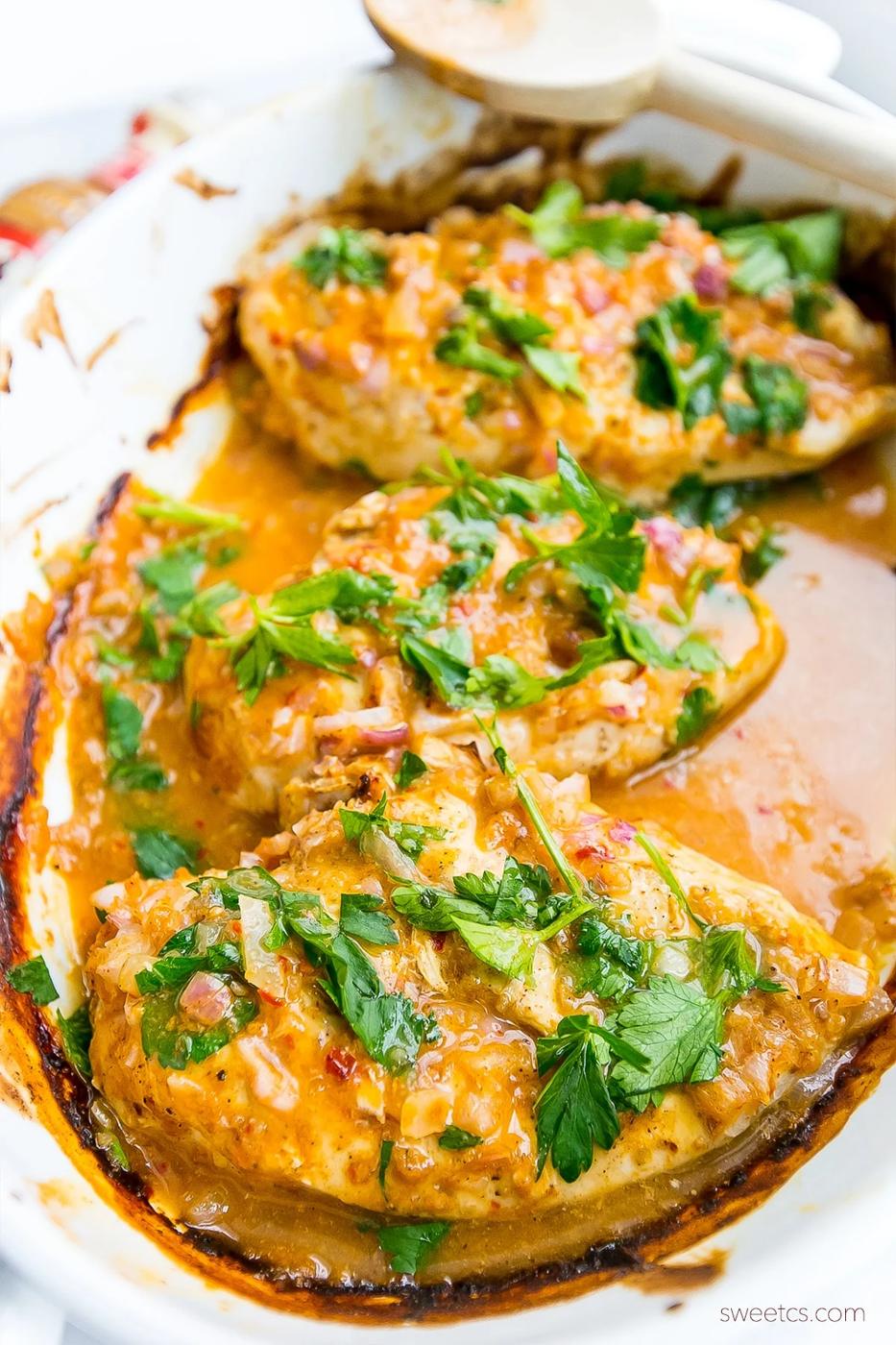 chicken in a pot with red sauce and fresh parsley on it