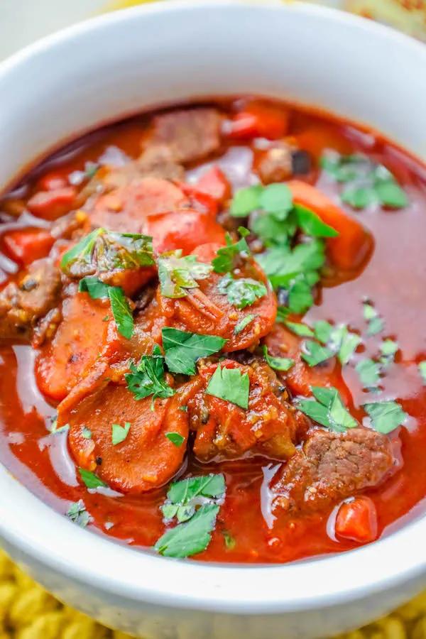 A bowl of Easy One Pot Authentic Hungarian Goulash Beef Stew, garnished with carrots and parsley.