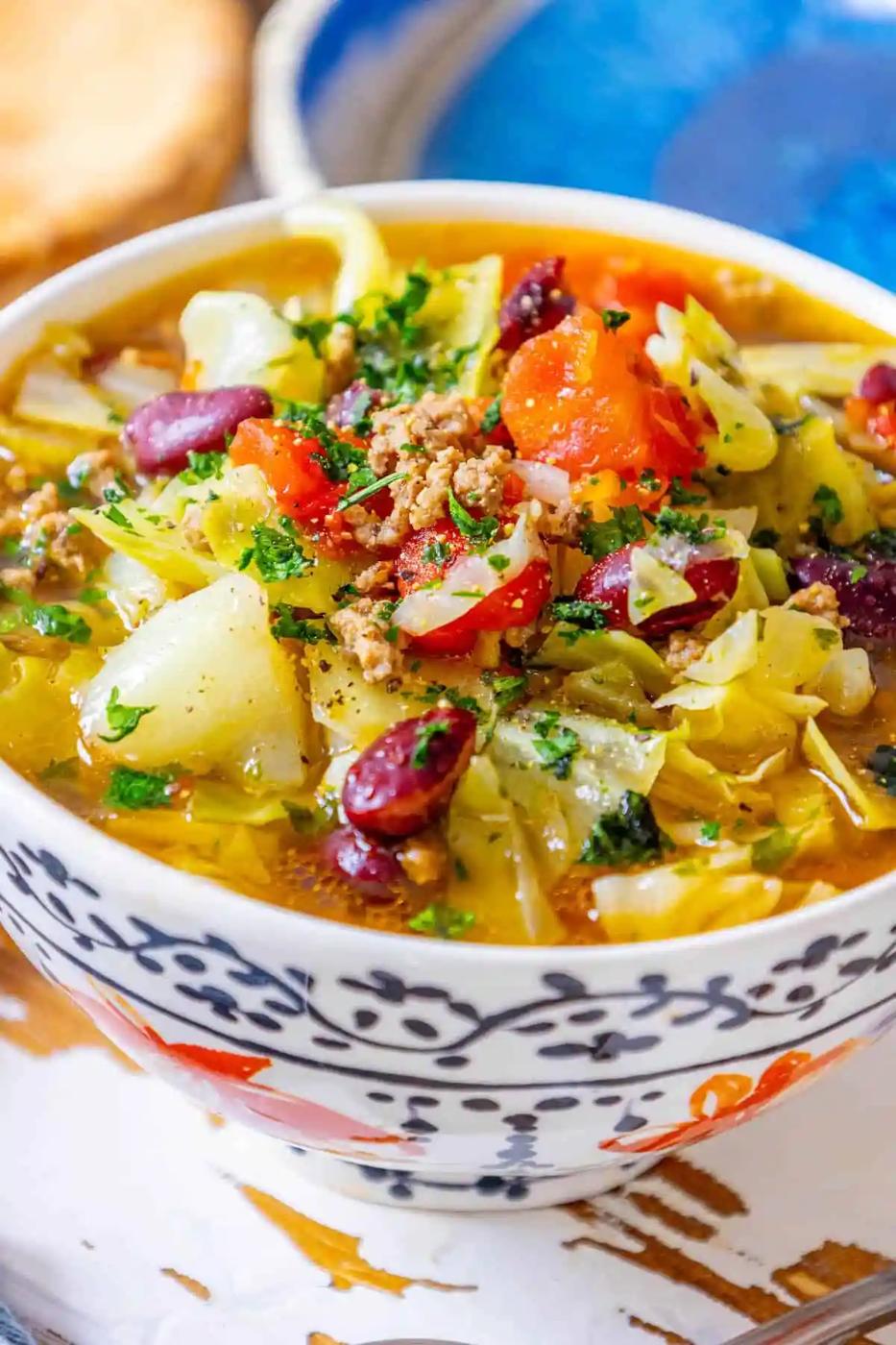 A bowl of cabbage soup with ground beef and vegetables.