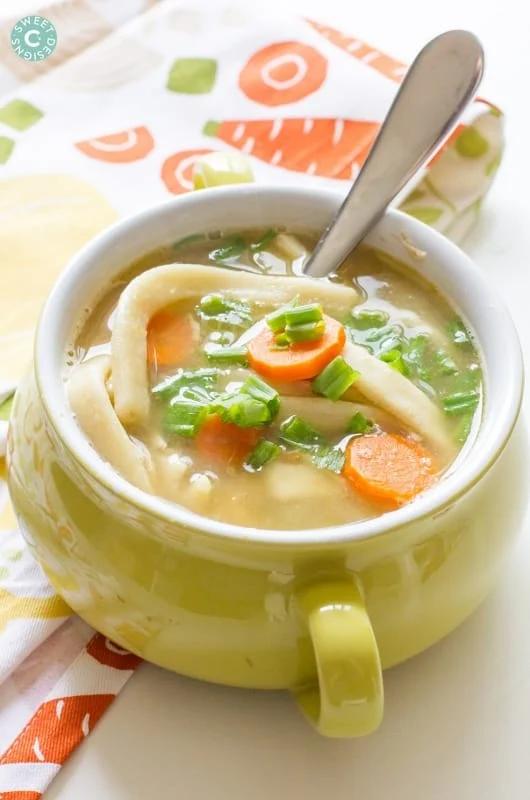 bowl of soup with noodles, carrots, and green onions on it