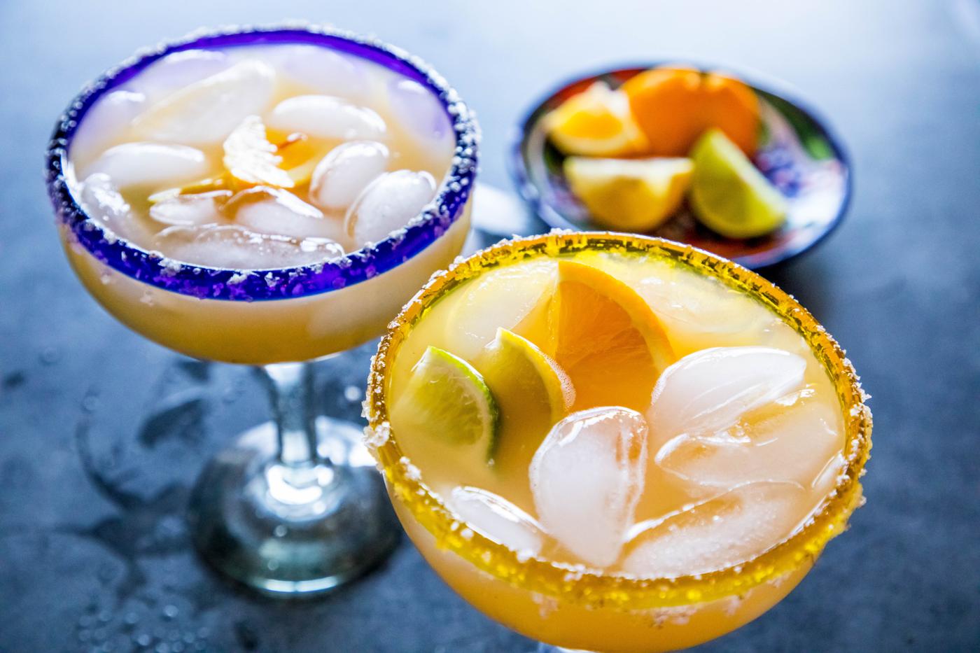 2 yellow margarita with lemon and lime wedges in it