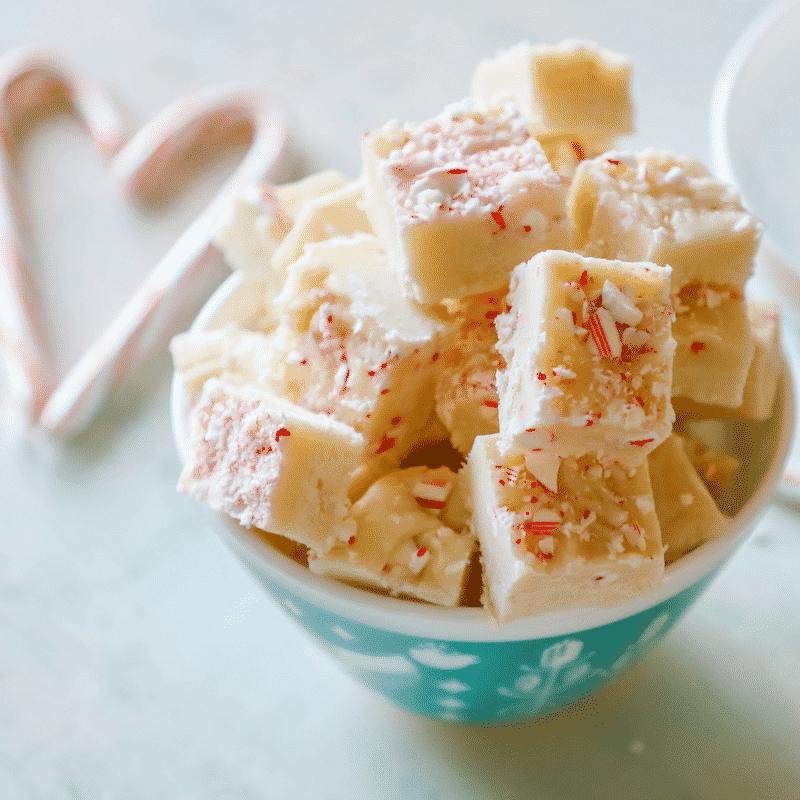 Peppermint fudge in a bowl with candy canes, made using an easy candy cane fudge recipe.