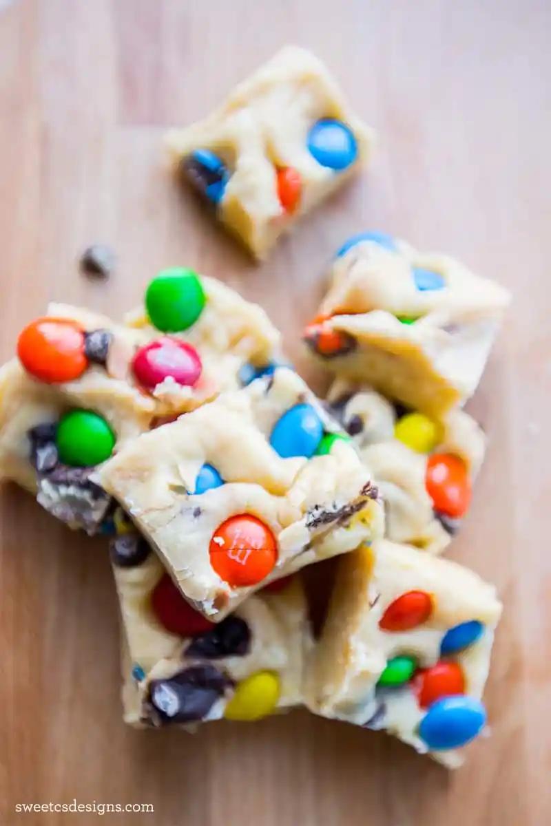 A piece of easy microwave m&m cookie dough fudge on a cutting board.
