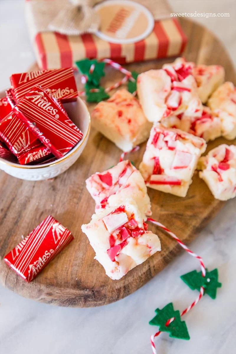 Peppermint bark adorned with candy canes and Andes candies on a cutting board.