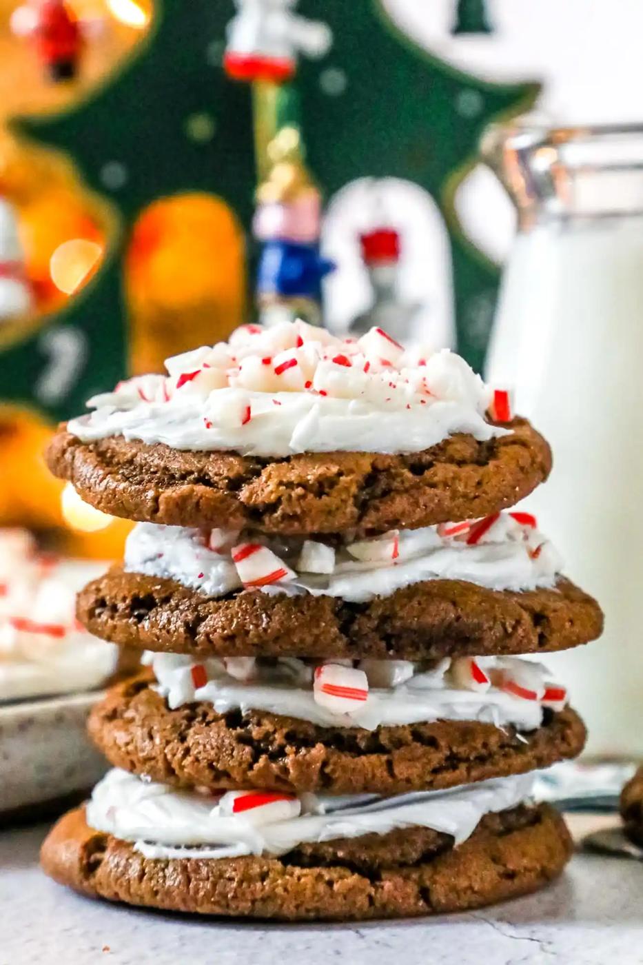 A stack of iced peppermint chocolate cookies with whipped cream and candy canes.