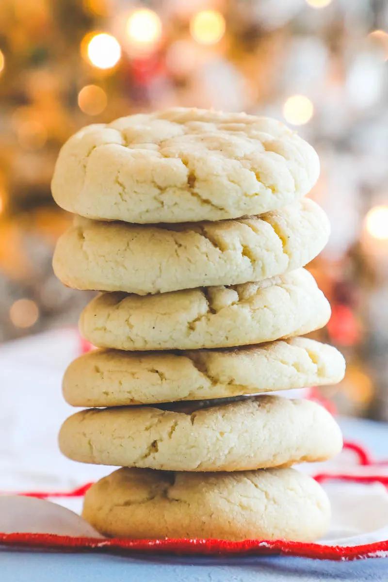 A stack of the best sugar cookies with a Christmas tree in the background.