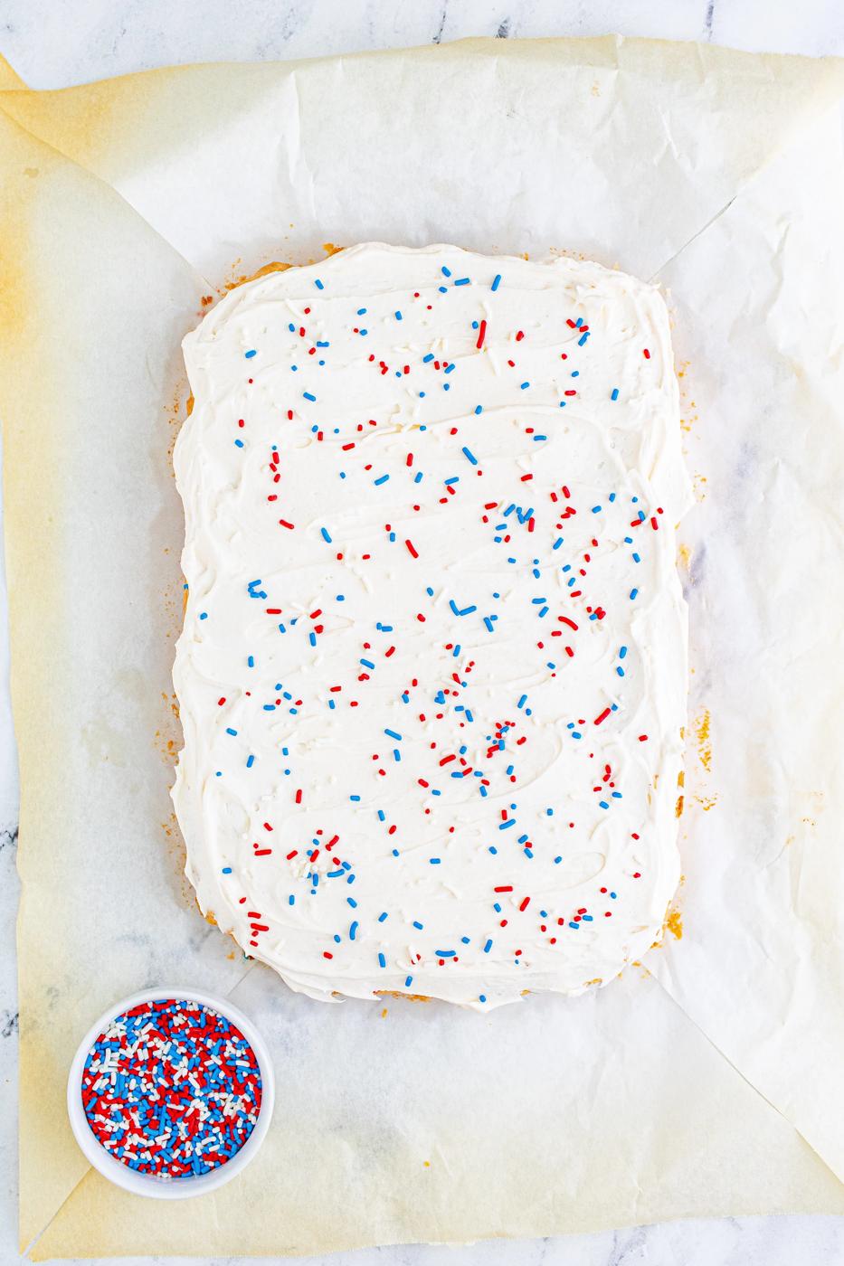 large bake covered in frosting and red white and blue sprinkles