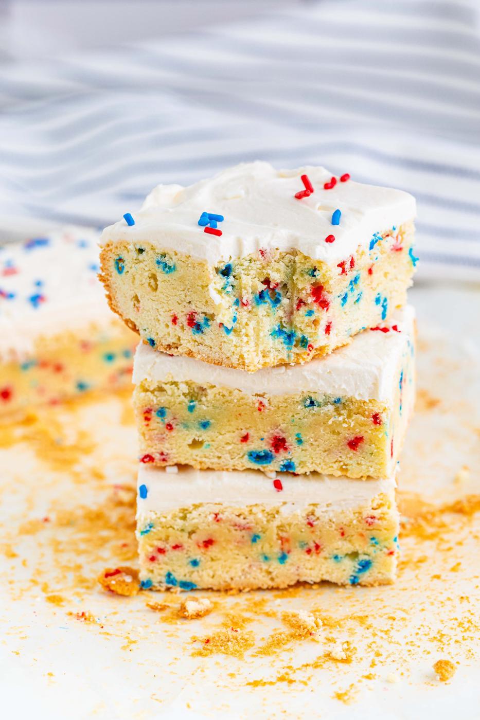 three vanilla bars with red and blue sprinkles in them and on frosting on top