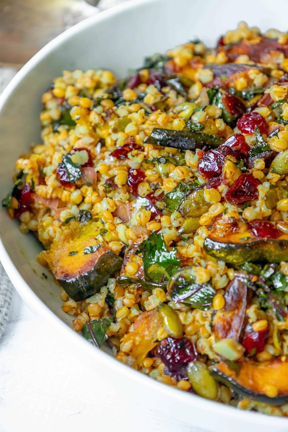 A white bowl with a mixture of vegetables and cranberries.