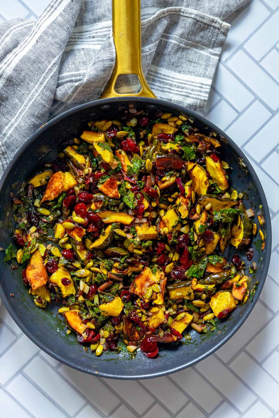A frying pan filled with vegetables and cranberries.