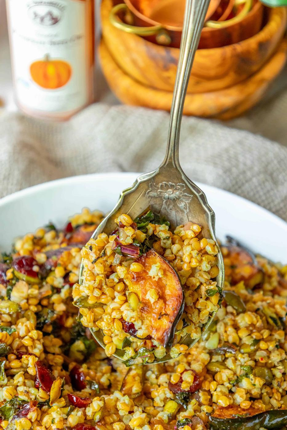 Farro salad with pumpkin seeds and cranberries in a white bowl.