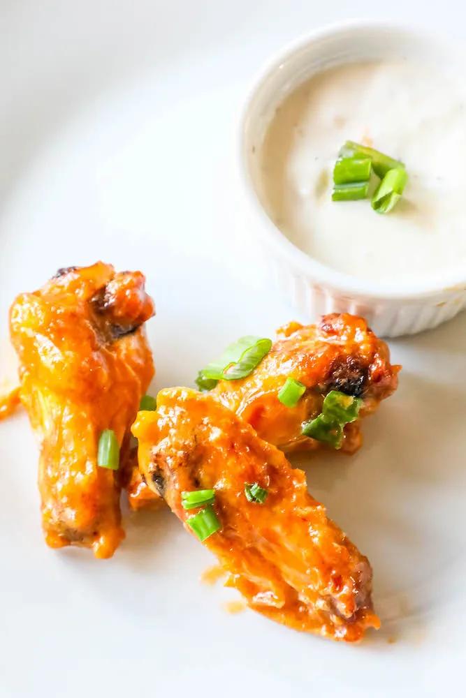Keto air fried Nandos chicken wings served with ranch dip on a white plate.