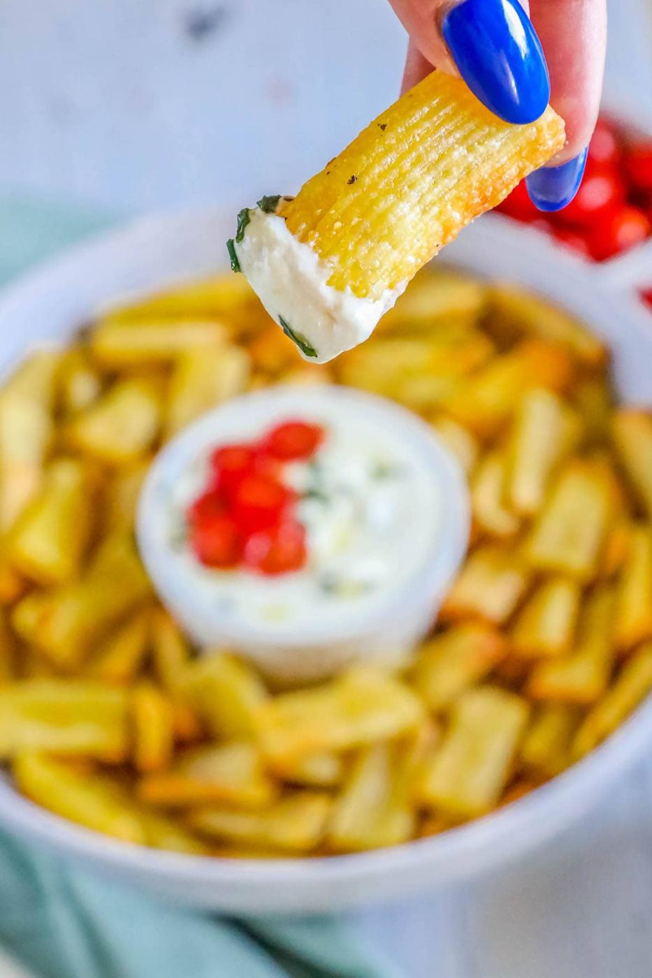 picture of air fried pasta chips in a bowl with feta dip with tomatoes sliced on top
