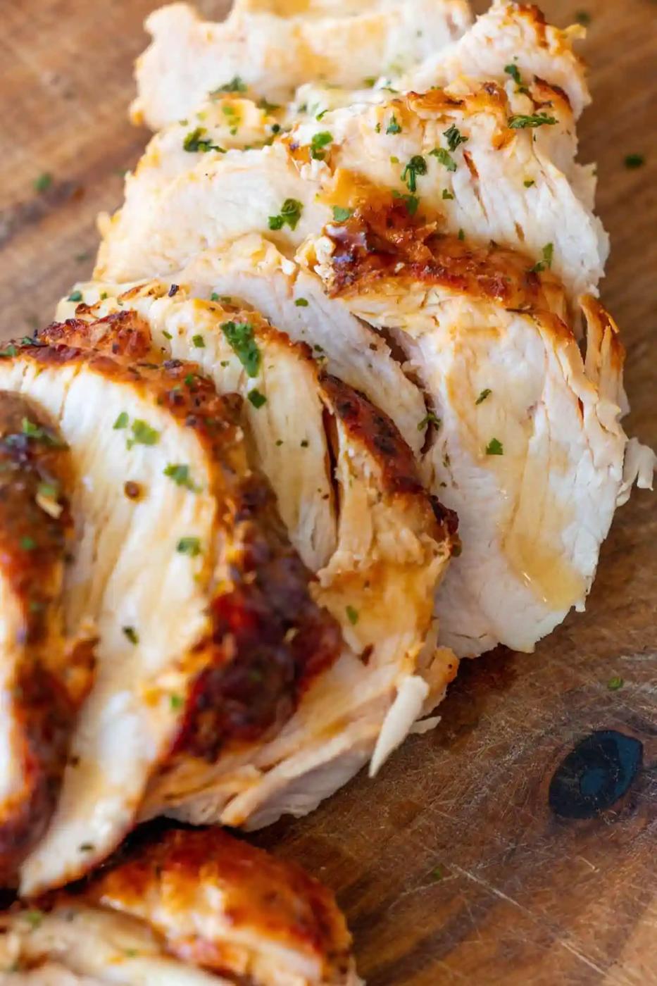 Slices of cooked, seasoned turkey breast arranged on a wooden cutting board.