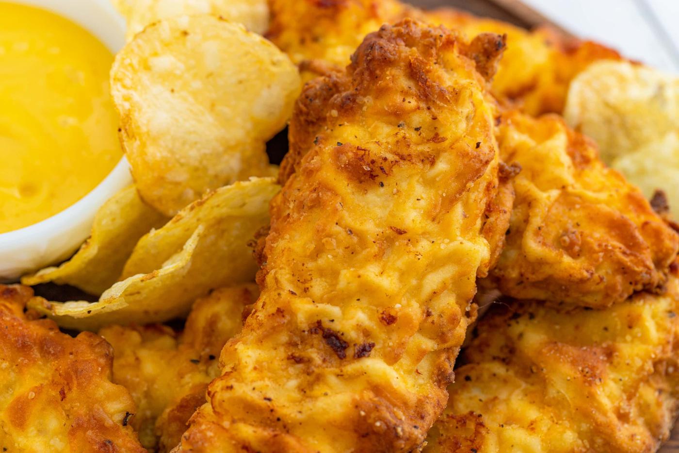 chicken tenders with sauce on the side with potato chips