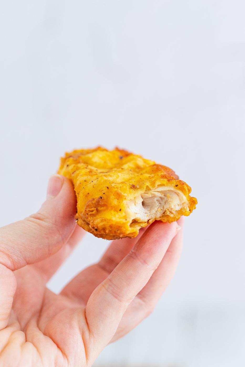 a chicken tender that has been bitten into being held up