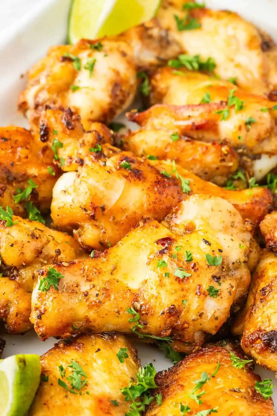 Air-fried chicken wings on a white plate with lime wedges.