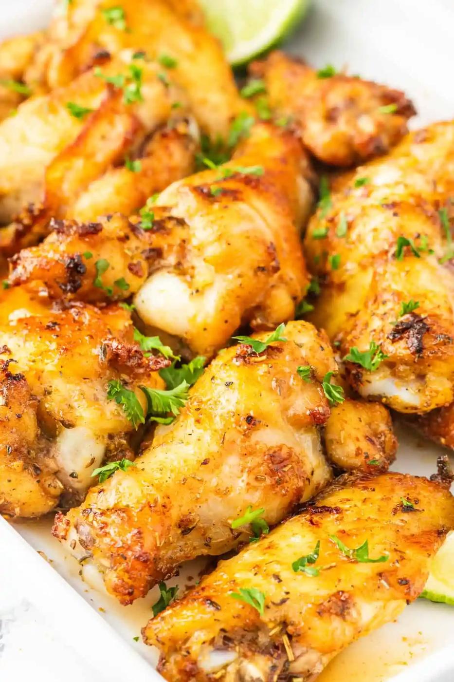 Air-fried Chicken Wings with lime wedges on a white plate.