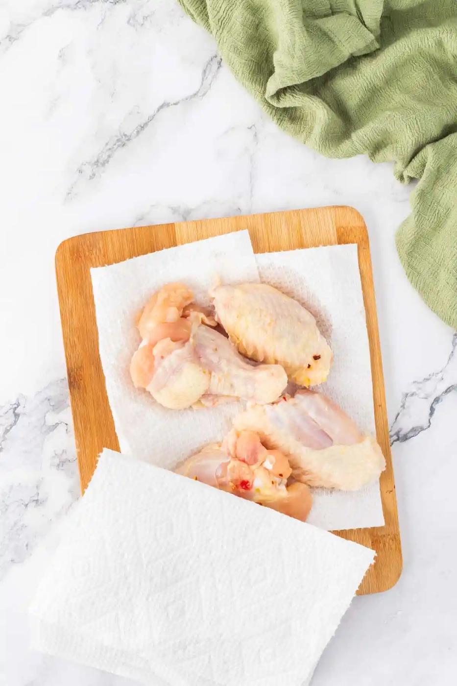 Chicken wings cooked to perfection in an air fryer, presented beautifully on a rustic wooden cutting board.