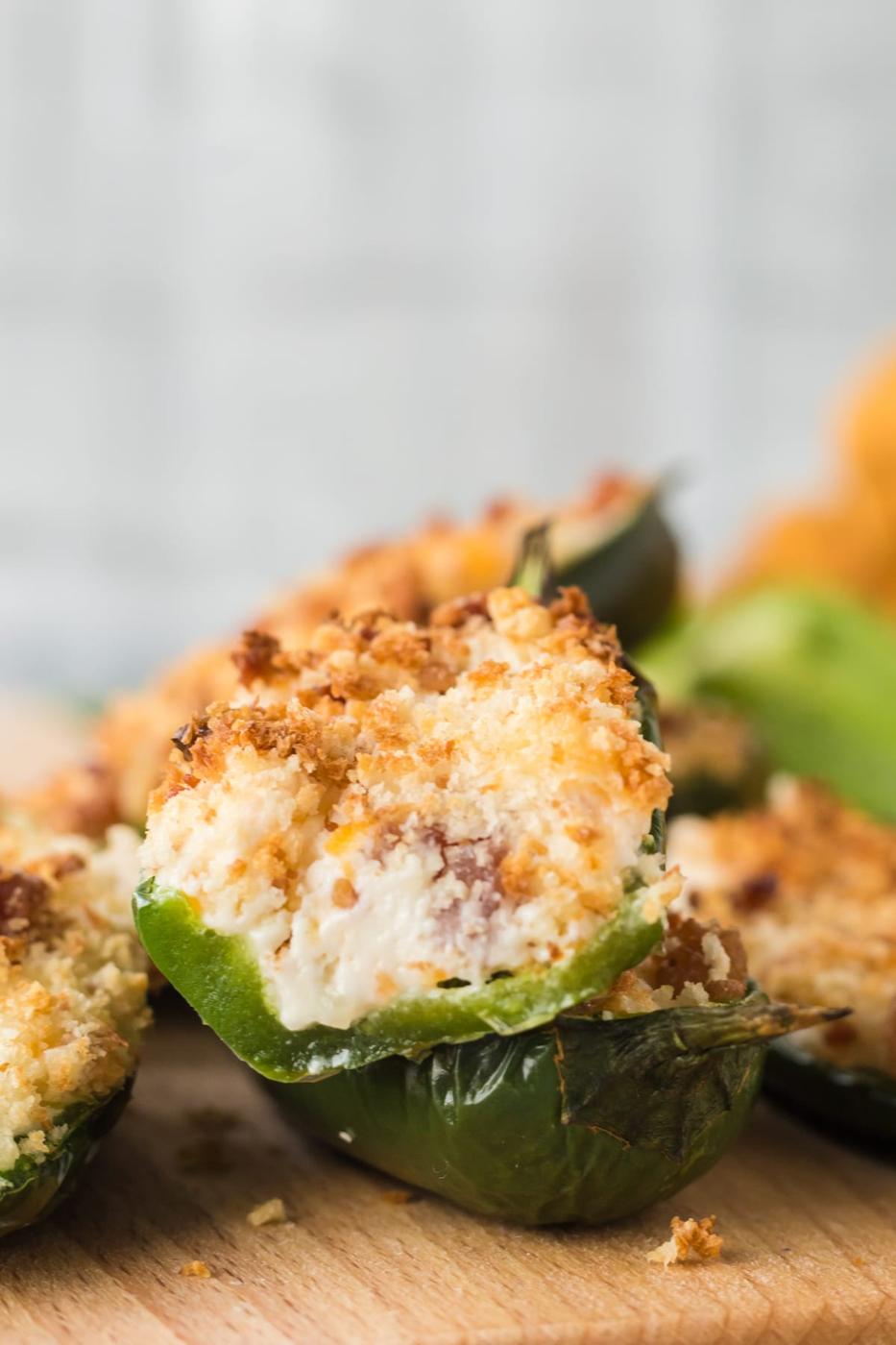 air fried browned jalapeño popper sliced in half and stacked on other jalapeño poppers on a plate