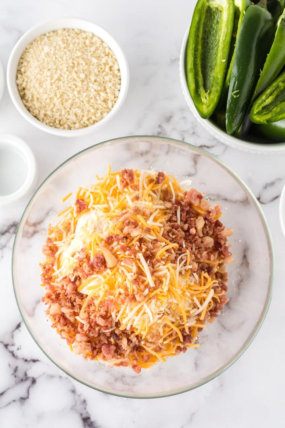 cream cheese, shredded jack cheese, crumbled bacon, onion powder, and garlic salt in a glass bowl on a table
