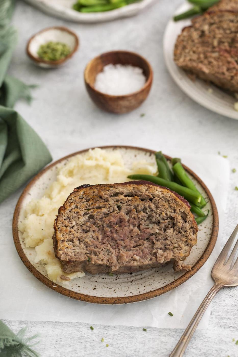 meatloaf on a plate with potatoes and green beans