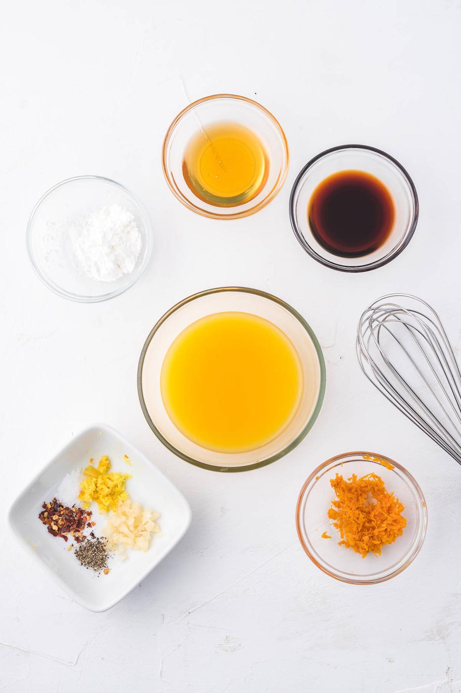 A bowl of ingredients for a curry dish with orange chicken and an air fryer on a white background.