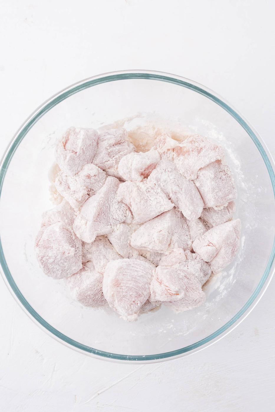 Shredded chicken in a glass bowl on a white background, perfect for an air fryer recipe.