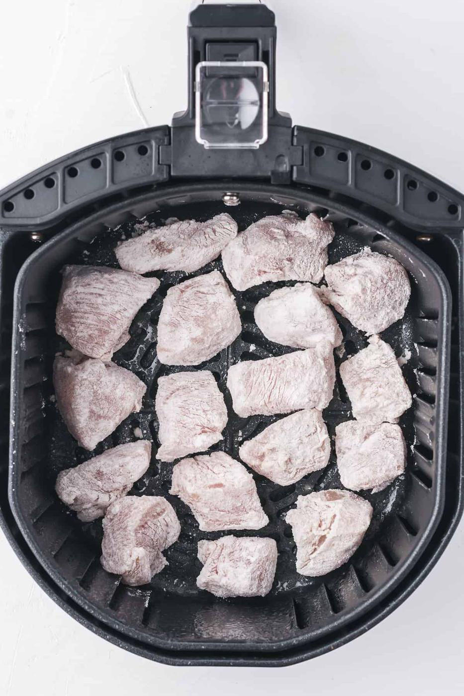 Orange chicken prepared in an air fryer on a white background.