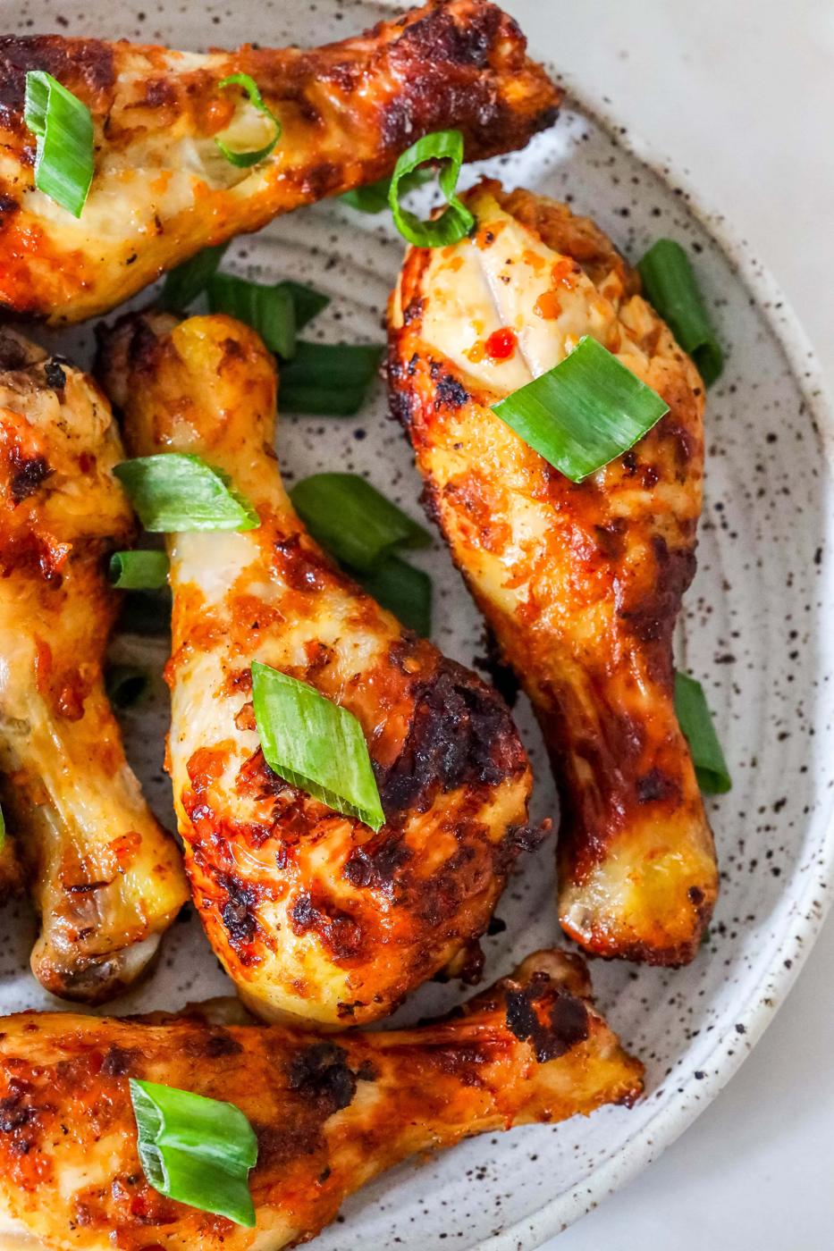 picture of spiced chicken drumsticks with green onions on it.