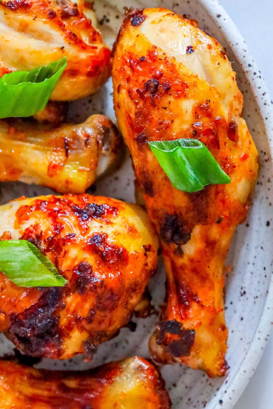 picture of spiced chicken drumsticks with green onions on it.