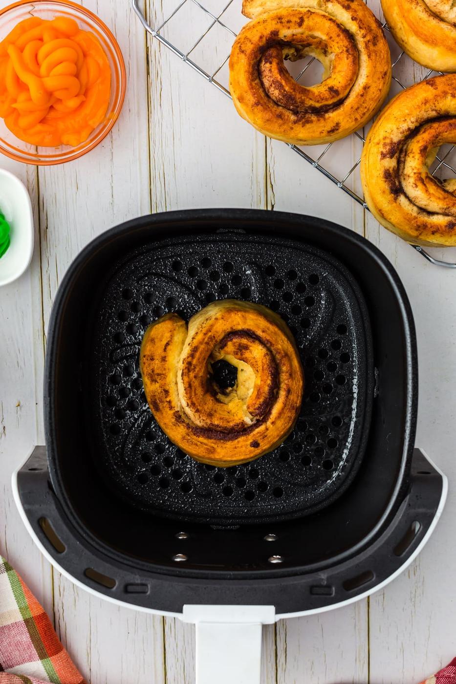 air fried cinnamon roll donuts in an air fryer basket