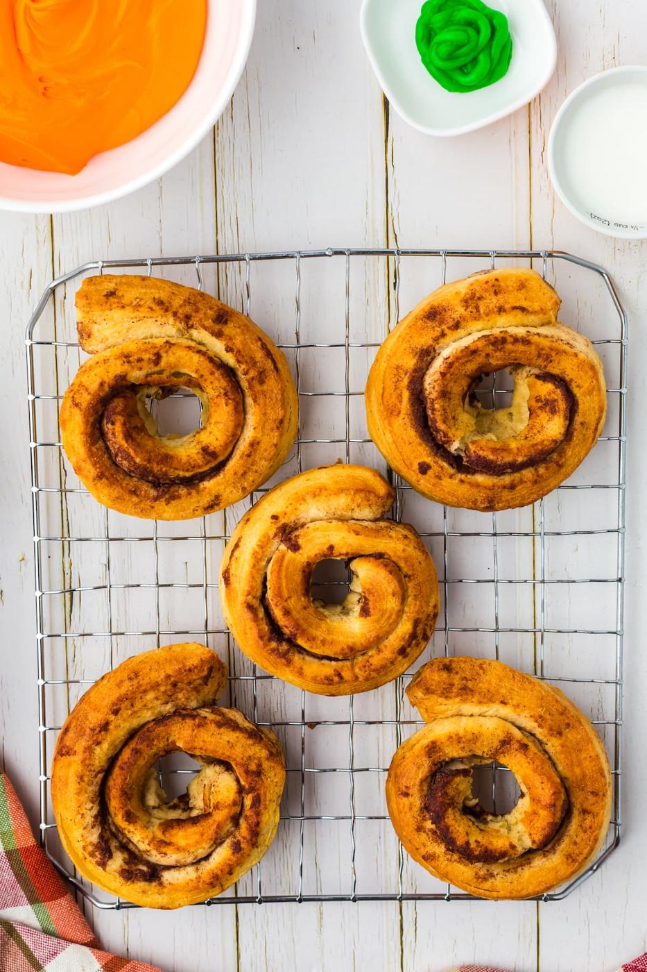 cinnamon roll donuts cooling on a cooling rack