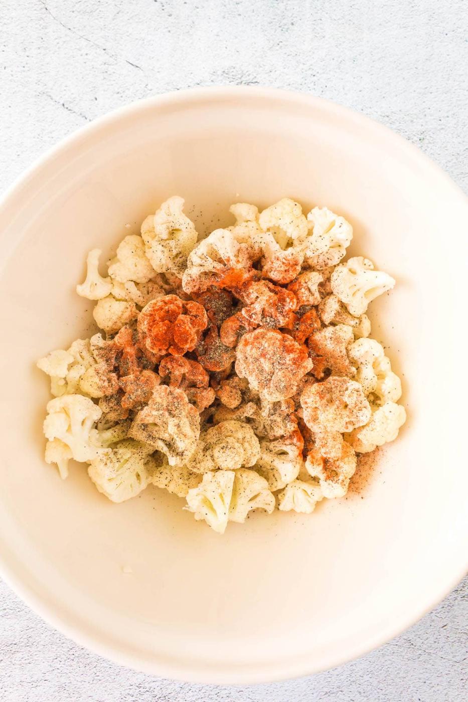 seasoning on raw cauliflower in a bowl