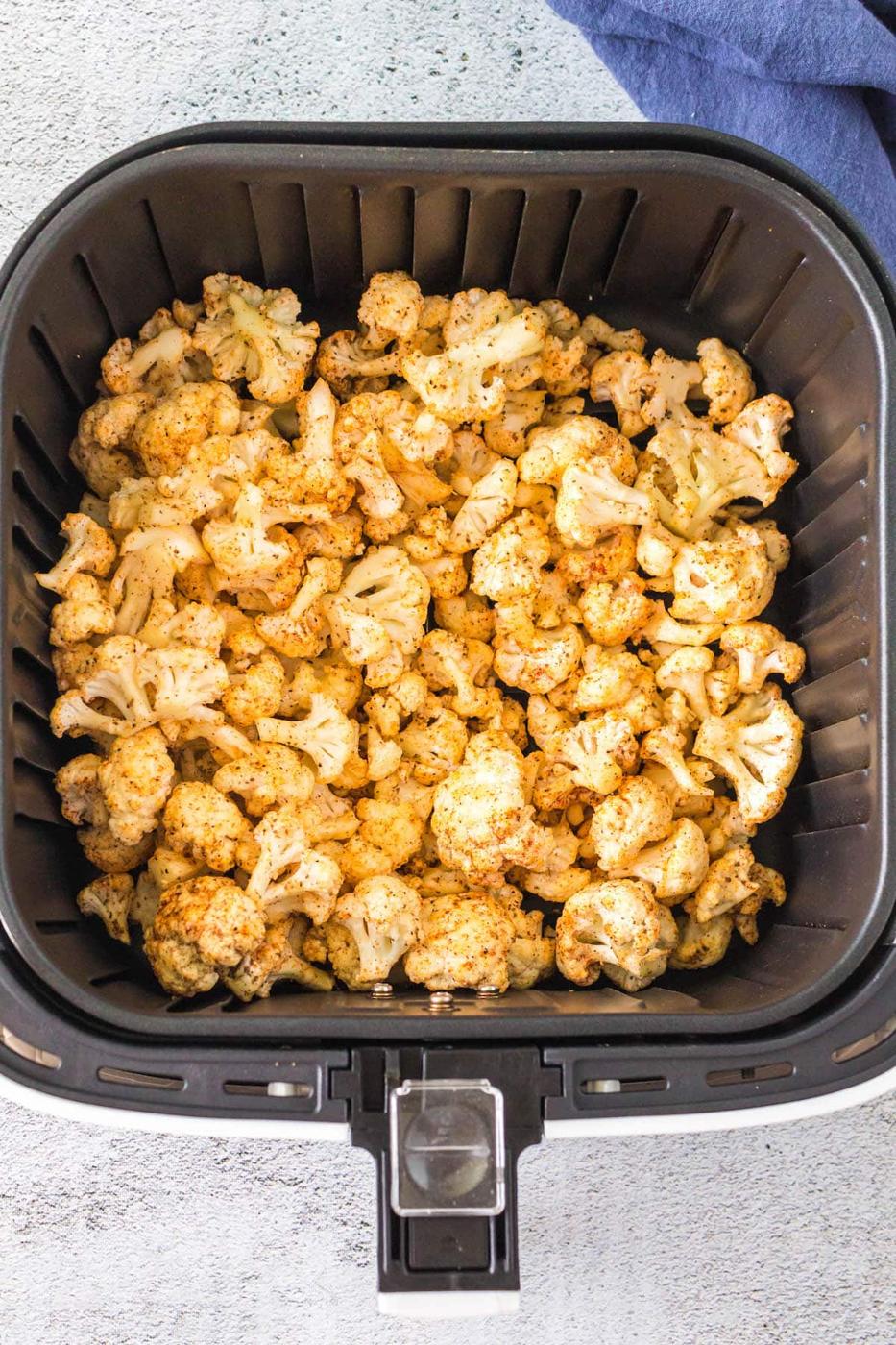 seasoned cauliflower in an air fryer basket
