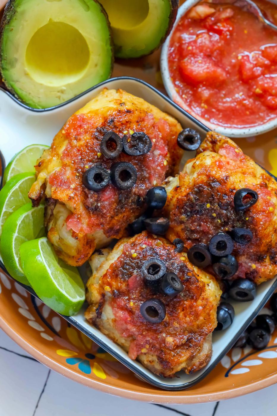Chicken enchiladas topped with avocado and salsa.