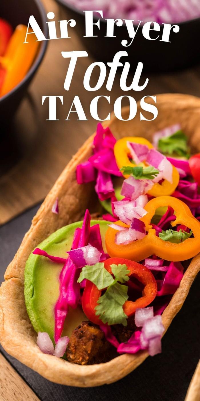 picture of air fried tofu taco on a table topped with avocado peppers and cabbage