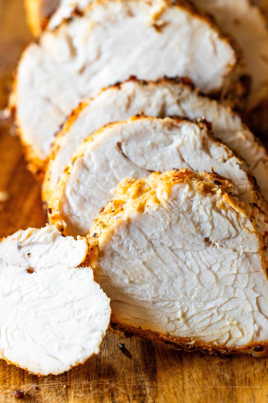 Sliced cooked turkey breast arranged on a wooden cutting board, perfect for serving after preparing in an air fryer.