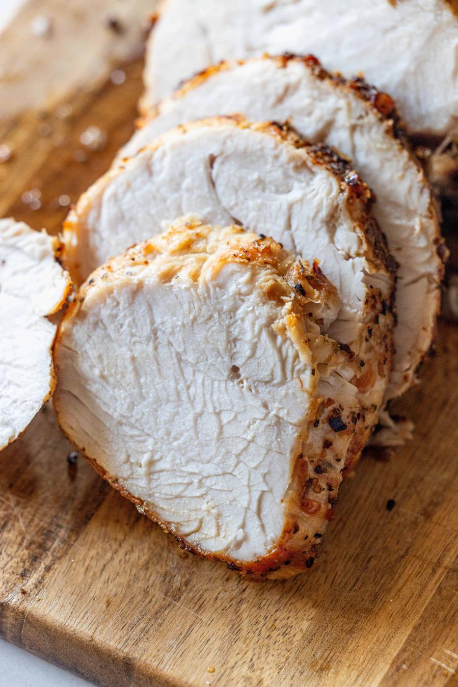 Sliced cooked turkey breast on a wooden cutting board, showing a seasoned and juicy interior—perfectly prepared in the air fryer for extra tenderness.