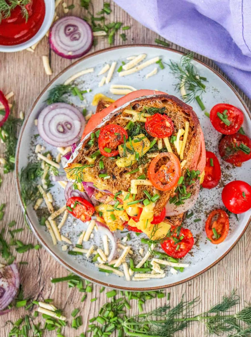A vegan sandwich with tomatoes and onions on a plate.