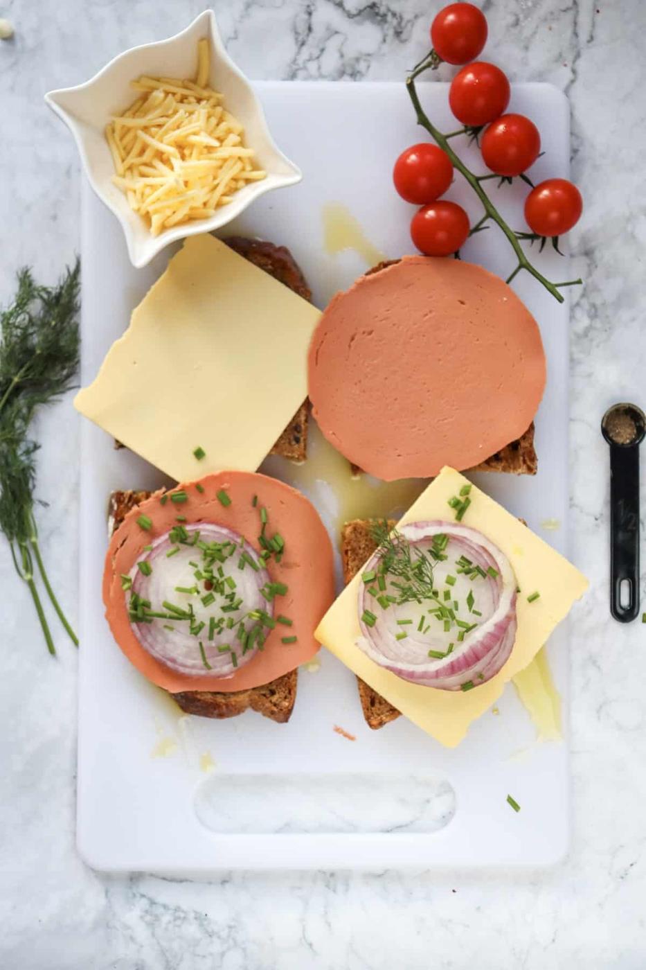 A white cutting board with a sandwich, tomatoes, and cheese.